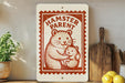 A wooden shelf with a potted plant, a wooden cutting board, and a sign that reads "HAMSTER PARENT" in a red and white design.