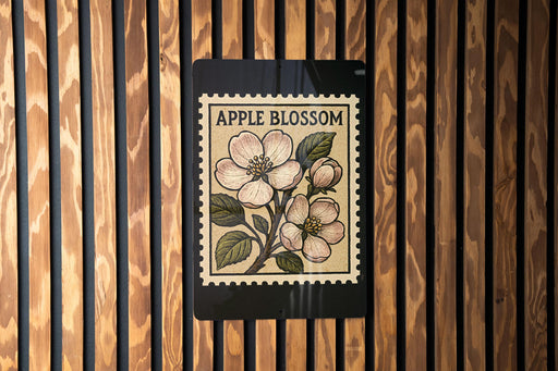 a wooden wall with a black and white stamp-like design depicting an apple blossom on a branch.