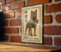 A metal sign featuring a dog, likely a kai dog, mounted on a brick wall.