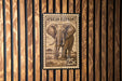 A wooden wall with a 25c African elephant stamp displayed on it.
