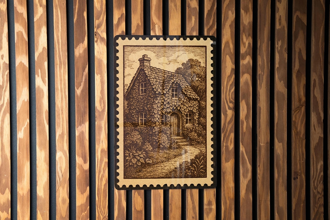 a wooden wall with a framed illustration of a house, which appears to be a cottage or a small building.
