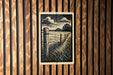 a wooden fence with a black and white illustration of a field and sky on it, mounted on a wooden wall.