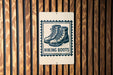 A sign with a graphic of hiking boots and the text "HIKING BOOTS" is displayed on a wooden wall.