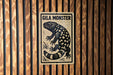 a sign with a black and white illustration of a spotted animal, which appears to be a type of lizard or salamander.