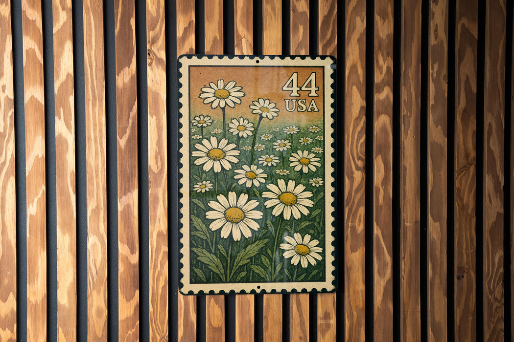 A framed image of a postage stamp with a field of white daisies and the number 44 printed on it, hanging on a wooden wall.