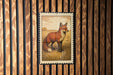 a framed illustration of a fox standing in a grassy field.