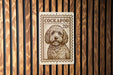A metal sign with a stamp-like design featuring a dog's portrait, mounted on a wooden wall.