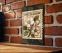 a brick wall with a framed illustration of an apple blossom on it.