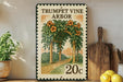 A vintage-style stamp depicting a garden scene with a wooden trellis and orange flowers, placed on a wooden shelf next to a wooden cutting board and a potted plant.