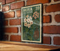 A vintage-style stamp with a floral design is displayed on a brick wall, featuring a collection of flowers and leaves.
