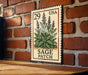 A metal sign with a stamp-like design, featuring a plant with purple flowers, mounted on a brick wall.