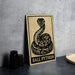 a sign with a snake and the text "BALL PYTHON" on it, placed on a table next to some black camera lenses.