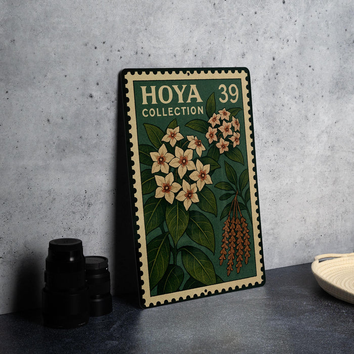 A metal stamp with a floral design and the text "HOYA COLLECTION 39" is displayed on a table next to some black camera lenses.