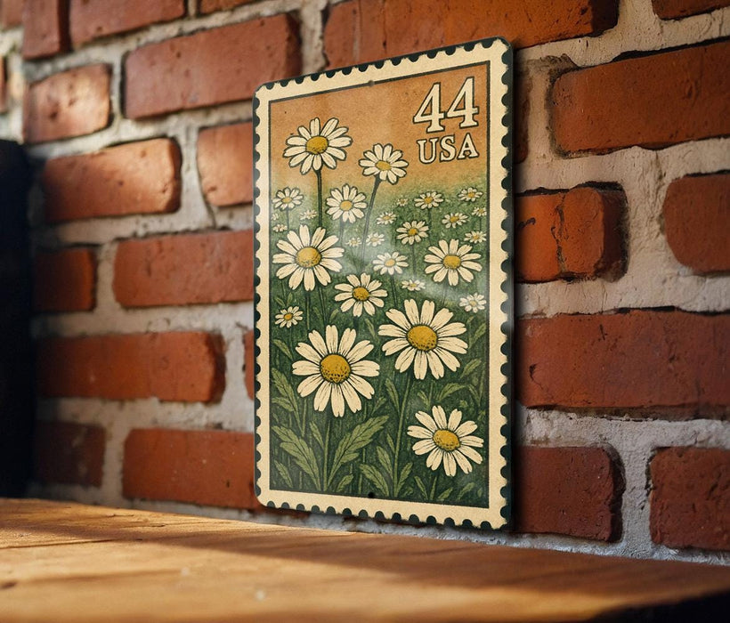 A framed print of a daisy flower design is hanging on a brick wall.