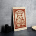 A metal sign with a hamster illustration and the text "HAMSTER PARENT" is displayed on a table.