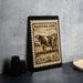 A framed stamp depicting a cow, with the text "PASTEURE COW" and "USA 10c" printed on it, is displayed on a table next to some black camera lenses.