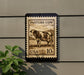 a stamp-like sign with a cow illustration, mounted on a wall next to a plant.