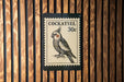 A black and white postage stamp featuring a detailed illustration of a cockatoo, with the text "COCKATIEL 30c" printed on it.