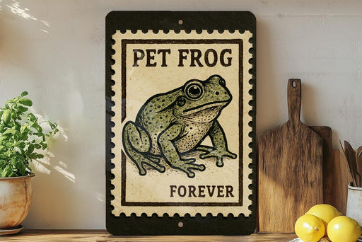 A framed image of a green frog with the text "PET FROG FOREVER" on it, placed on a shelf next to a wooden cutting board and a potted plant.