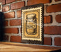 A vintage-style metal sign with a honey jar illustration is mounted on a brick wall.