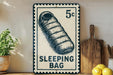 A vintage-style metal sign with a sleeping bag illustration, placed on a wooden surface next to a wooden cutting board and some lemons.