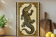 a decorative ceramic plate with a detailed illustration of a crocodile, placed on a wooden surface next to a wooden cutting board and a potted plant.