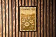 a framed poster of a field of flowers, specifically chamomile flowers, hanging on a wooden wall.