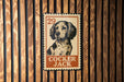 A metal stamp featuring a dog's head and the text "COCKER JACK" is displayed on a wooden wall.