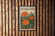 A framed image of marigold flowers is displayed on a wooden wall.