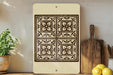 a decorative tile with a floral pattern, displayed on a shelf next to kitchen utensils and a potted plant.