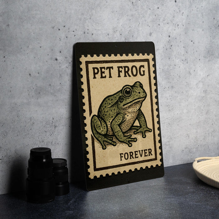 A framed poster of a frog is displayed on a wall, with a stamp-like border and the text "PET FROG FOREVER" printed on it.