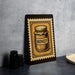 a framed illustration of a jar of honey on a wall, with a stack of black camera lenses placed next to it.