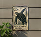 A 20 cent postage stamp featuring a sea turtle, mounted on a wall next to a plant.