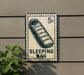 A sign with a sleeping bag illustration and the text "SLEEPING BAG" is mounted on a wall.