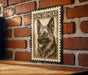 A framed image of a German Shepherd dog is displayed on a brick wall.