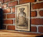 a wooden table with a framed illustration of a bag hanging on a brick wall.