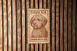 A metal sign with a Spanish water dog illustration is mounted on a wooden wall.