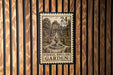 A formal English garden postage stamp is displayed on a wooden wall.