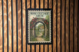 A framed illustration of a cottage with a garden path and a rose arch is displayed on a wooden wall.