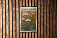 A vintage-style postage stamp featuring a floral illustration is displayed on a wooden wall.