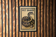 A framed image of a pet snake is displayed on a wooden wall.