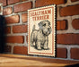 A framed illustration of a Sealyham Terrier dog is displayed on a brick wall.