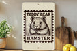 A framed image of a teddy bear is displayed on a shelf, with a wooden cutting board and a potted plant nearby.