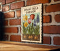 A vintage-style sign with illustrations of tulips and daffodils, mounted on a brick wall.