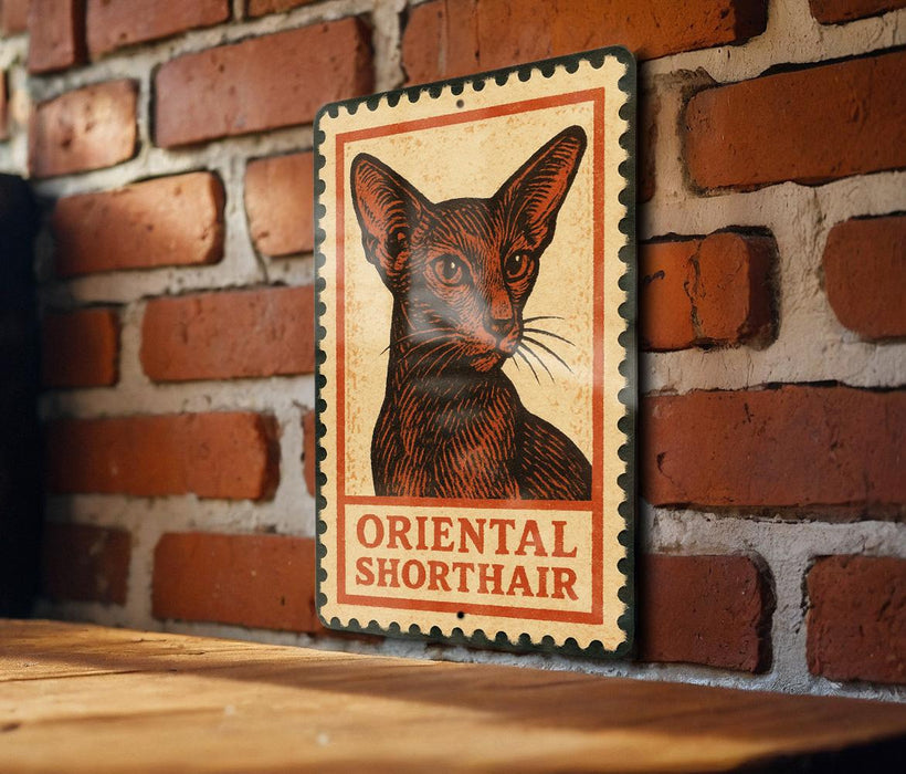 A metal sign featuring an illustration of an Oriental Shorthair cat is mounted on a brick wall.