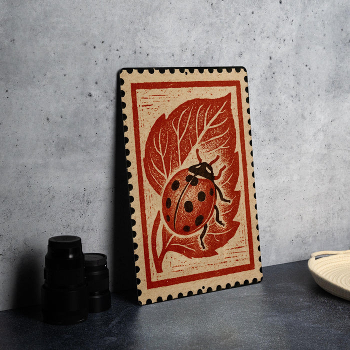 a wooden frame with a ladybug design on it, placed on a table next to some black camera lenses.