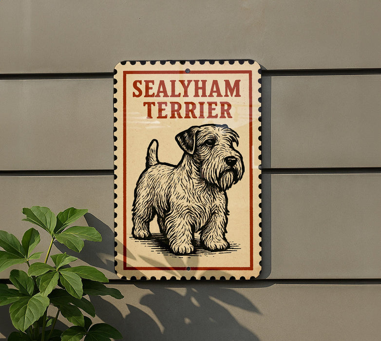 A sign for a Sealyham Terrier dog is displayed on a wall, with a plant visible to the left.