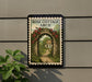A framed illustration of a rose archway leading to a quaint cottage, with a path leading up to the entrance.
