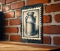 a brick wall with a metal sign featuring a black and white illustration of a milk can.