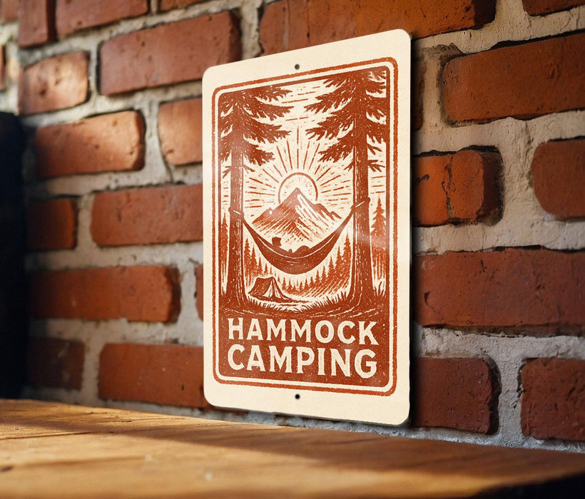 A sign with a hammock and camping scene is mounted on a brick wall.
